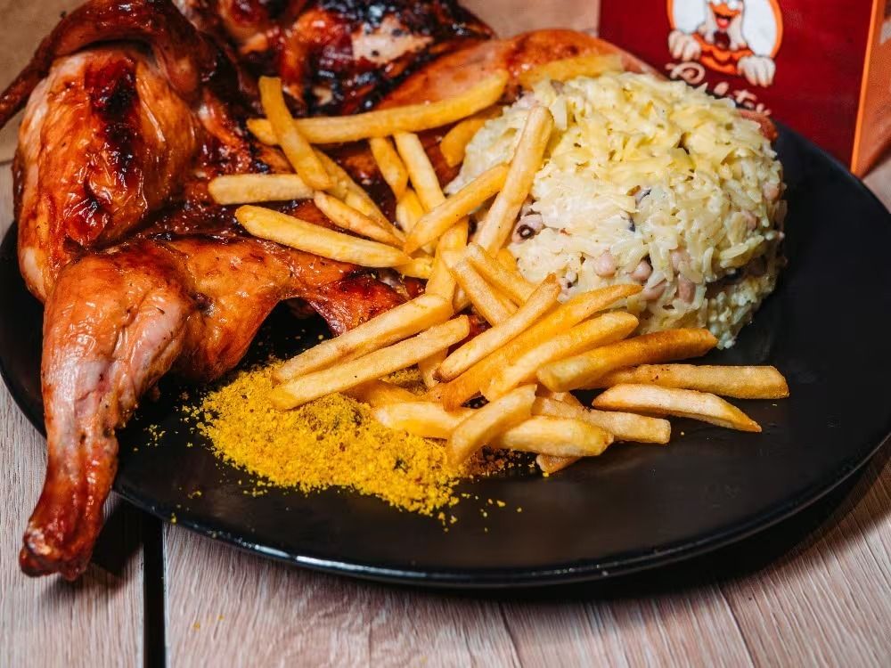 Galeto assado na brasa com baião de dois cremoso, batata frita e farofa, em Fortaleza
