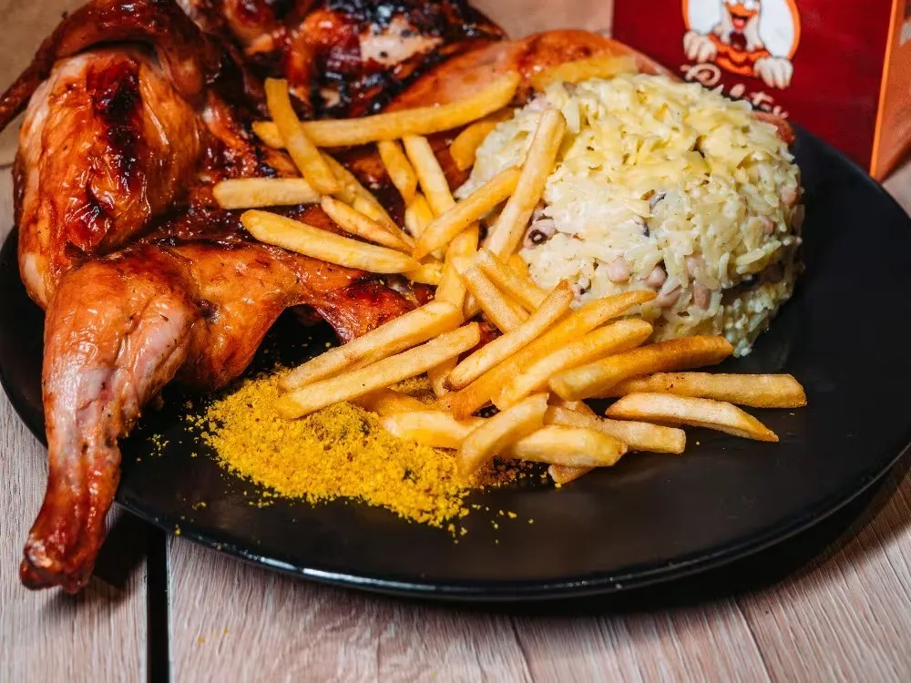 Prato montado com galeto assado, batata frita e baião de dois